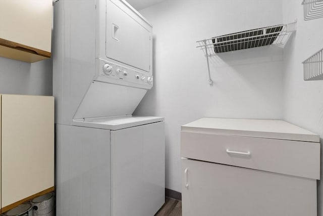 clothes washing area featuring laundry area, stacked washer / drying machine, and dark wood finished floors