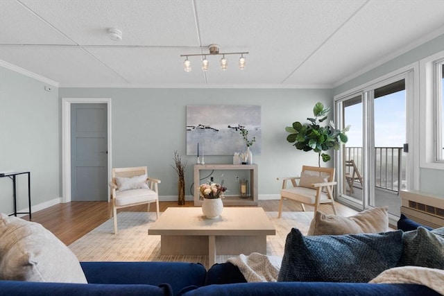 living area with baseboards, ornamental molding, a textured ceiling, and wood finished floors
