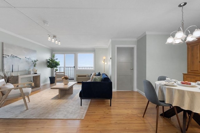 living area featuring crown molding, a chandelier, baseboards, and light wood-style flooring