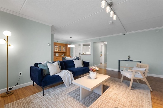 living area with crown molding, light wood-style flooring, and baseboards