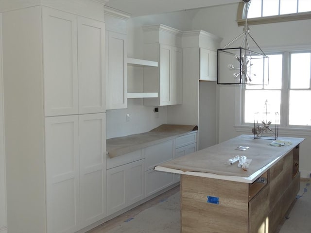 kitchen featuring white cabinets, a center island, a chandelier, and hanging light fixtures