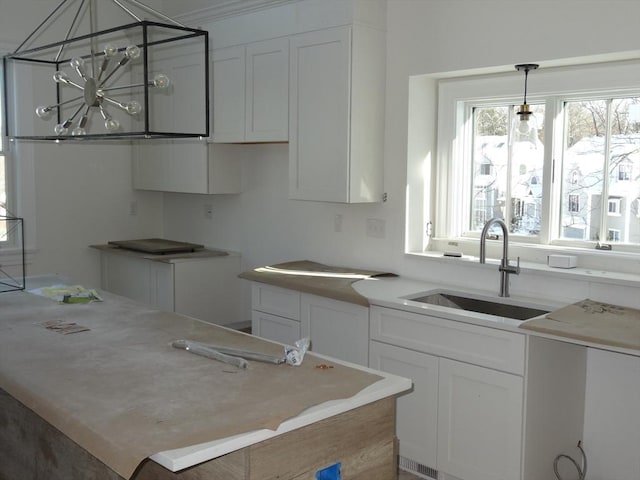 kitchen featuring pendant lighting, white cabinetry, sink, and an inviting chandelier