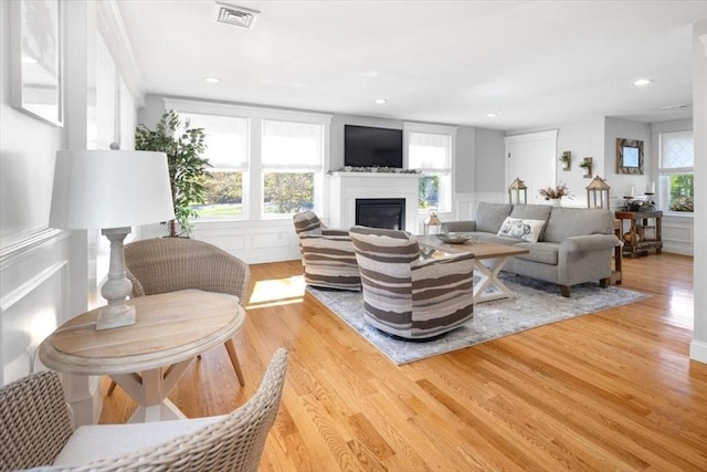 living area featuring light wood-style floors, visible vents, and a decorative wall