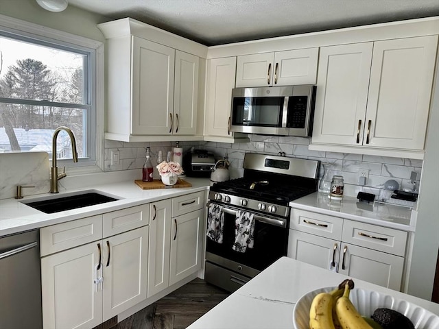 kitchen featuring sink, stainless steel appliances, white cabinetry, and light stone countertops