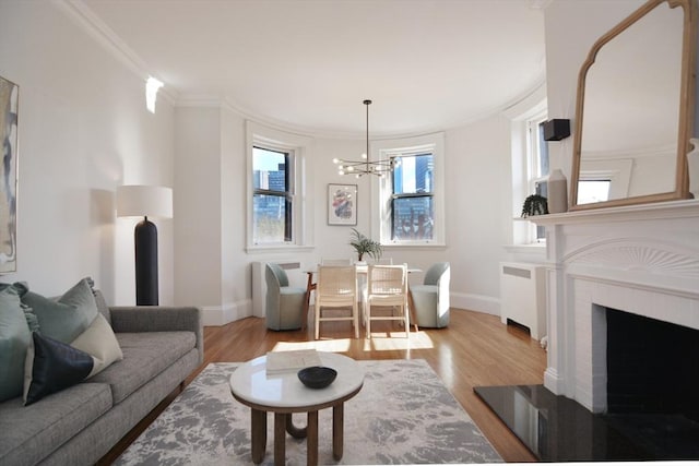 living room with crown molding, baseboards, a chandelier, radiator heating unit, and wood finished floors