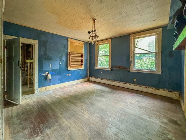 unfurnished room featuring baseboard heating and wood-type flooring