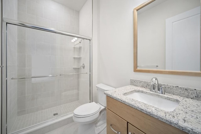 bathroom with vanity, a shower with shower door, and toilet