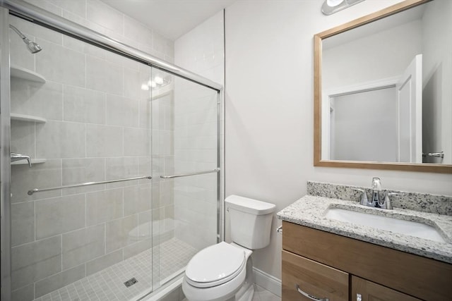 bathroom featuring vanity, a shower with door, and toilet