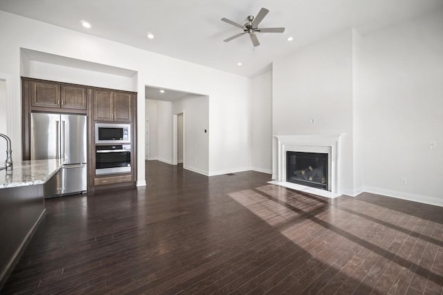 unfurnished living room featuring ceiling fan, dark hardwood / wood-style floors, and a high end fireplace