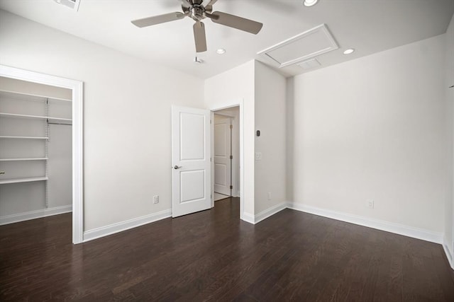 unfurnished bedroom featuring a spacious closet, dark wood-type flooring, ceiling fan, and a closet