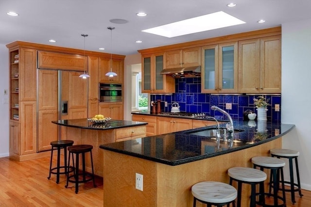 339 N St, Medfield, MA 02052 - kitchen with stainless steel appliances, a skylight, a breakfast bar, light wood-style flooring, and a peninsula
