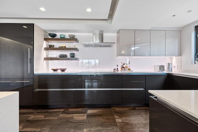 kitchen with island range hood, modern cabinets, light countertops, white cabinets, and stainless steel fridge
