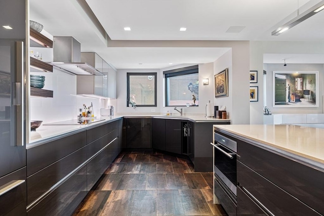 kitchen featuring wall chimney exhaust hood, stainless steel oven, black electric cooktop, and modern cabinets