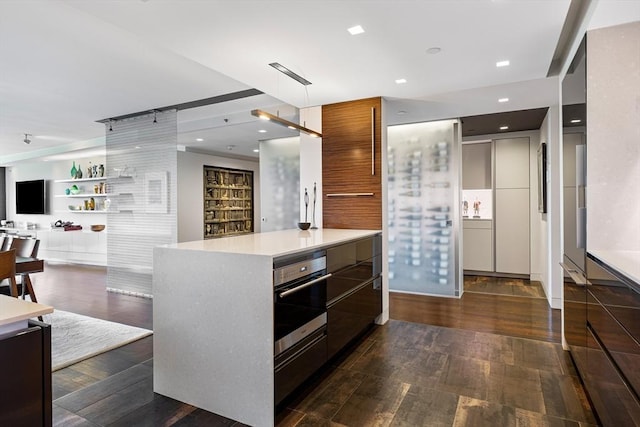 kitchen with modern cabinets, dark wood finished floors, light countertops, open floor plan, and oven