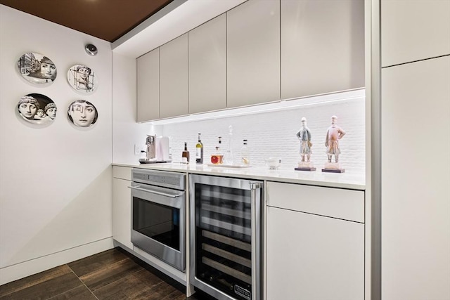 bar with wine cooler, indoor wet bar, stainless steel oven, dark wood finished floors, and backsplash