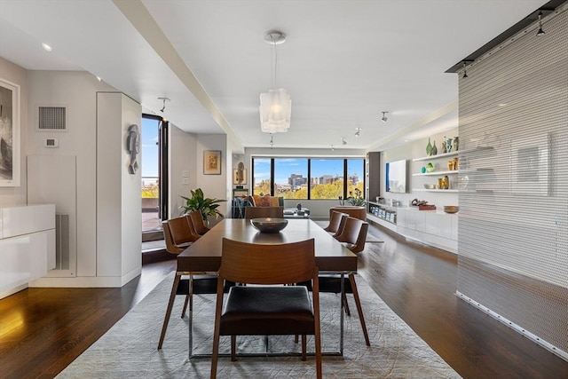 dining space with visible vents, baseboards, wood finished floors, and track lighting