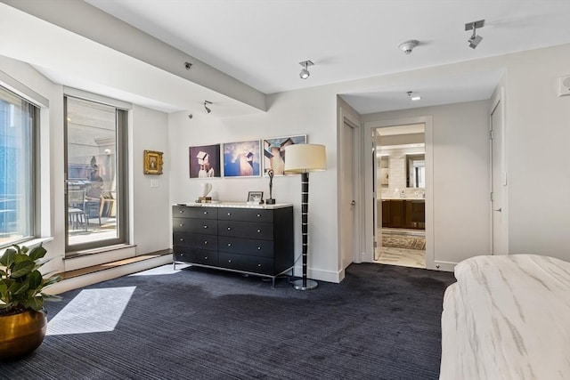 bedroom featuring baseboards, ensuite bath, access to exterior, and dark colored carpet