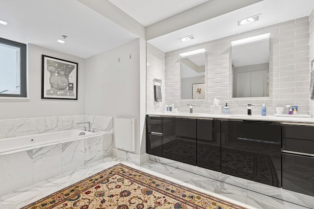 full bath featuring a garden tub, double vanity, and marble finish floor