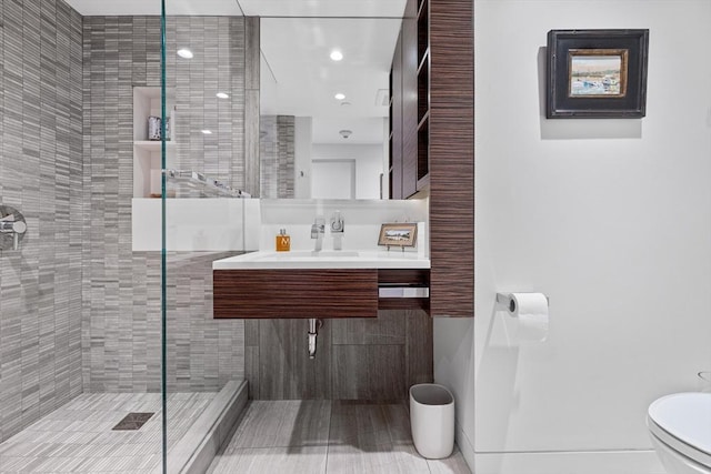 full bathroom with a sink, toilet, and tiled shower