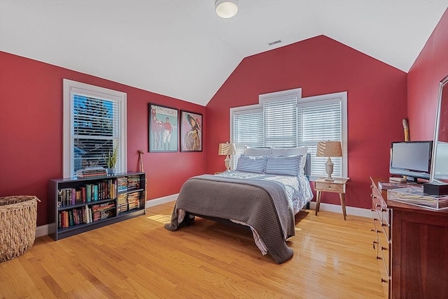 bedroom with light wood-type flooring, baseboards, visible vents, and lofted ceiling