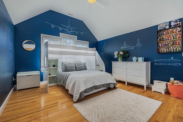 bedroom with baseboards, visible vents, vaulted ceiling, and wood finished floors