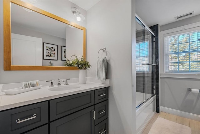 full bathroom featuring baseboards, visible vents, bath / shower combo with glass door, and vanity