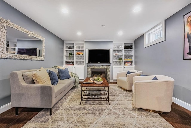 living room with built in shelves, a fireplace, recessed lighting, wood finished floors, and baseboards