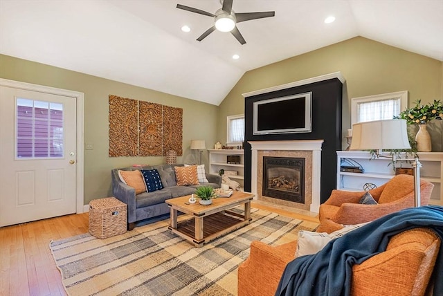 living area featuring ceiling fan, recessed lighting, a fireplace, vaulted ceiling, and light wood finished floors