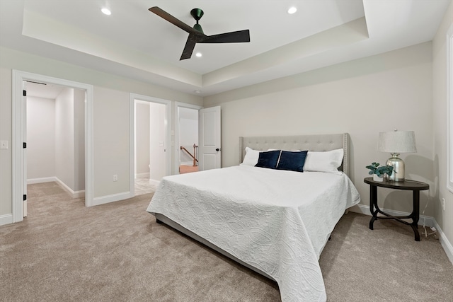 carpeted bedroom with a tray ceiling and ceiling fan