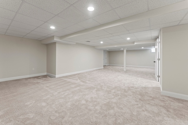 basement featuring light carpet and a paneled ceiling