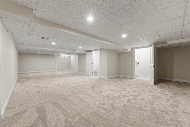 basement featuring a paneled ceiling and light colored carpet