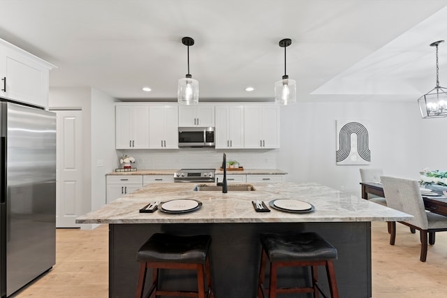 kitchen featuring a center island with sink, sink, appliances with stainless steel finishes, and light hardwood / wood-style floors