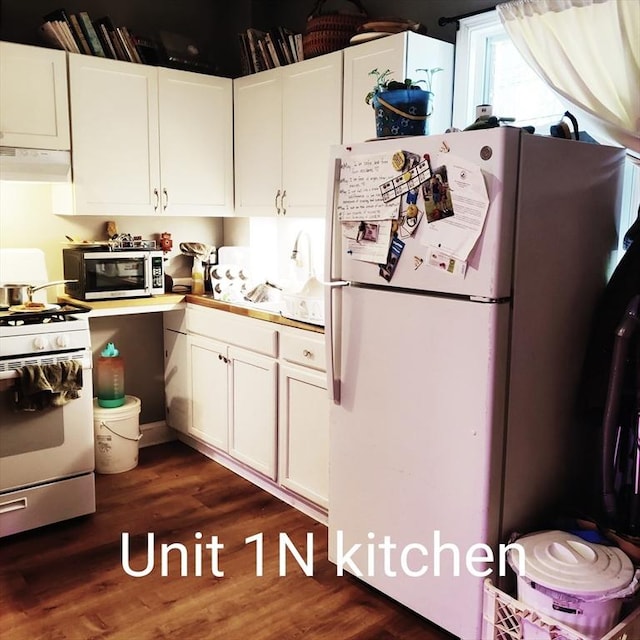 kitchen featuring white appliances, exhaust hood, dark wood finished floors, and white cabinetry