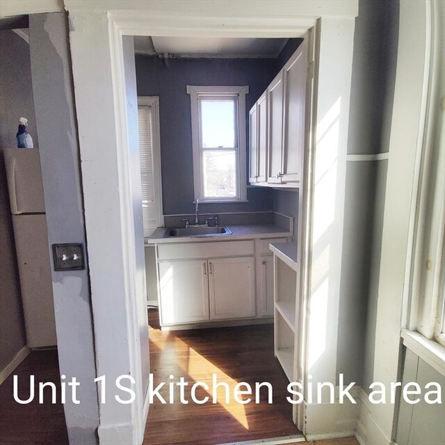 kitchen with a sink, dark wood-style floors, and white cabinetry