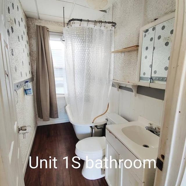 full bathroom featuring curtained shower, toilet, a freestanding tub, wood finished floors, and vanity