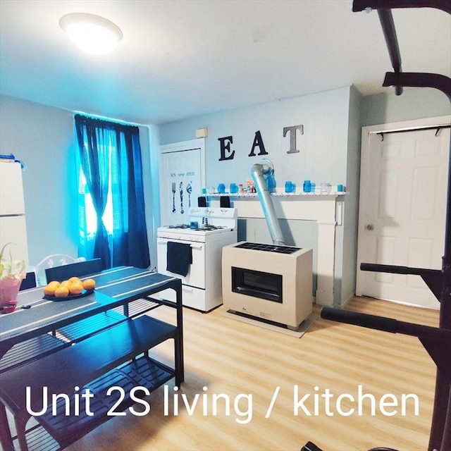 kitchen with white appliances, a wood stove, and wood finished floors