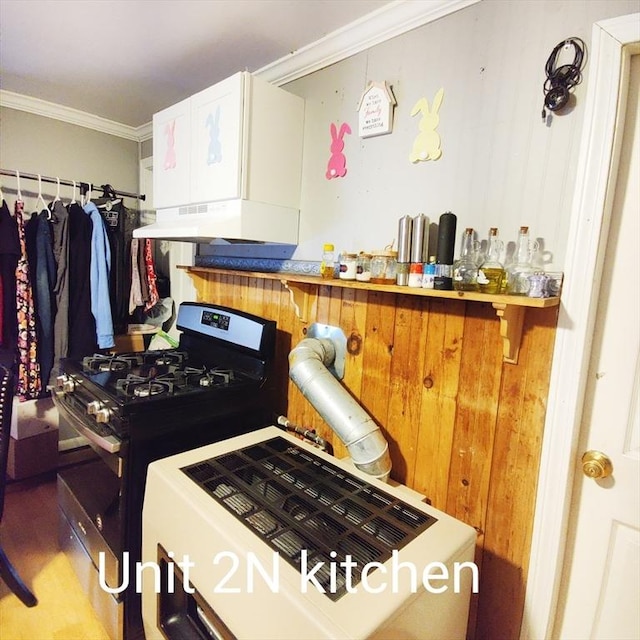 kitchen featuring stainless steel gas range oven, a breakfast bar, under cabinet range hood, white cabinetry, and crown molding