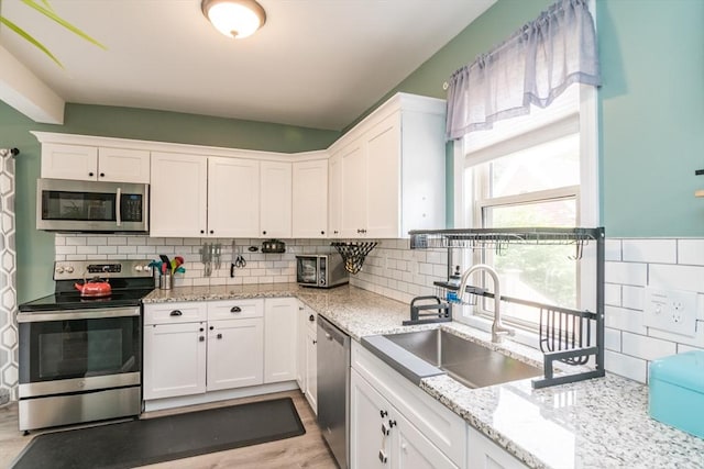61 Fairfield Ave, Holyoke, MA 01040 - kitchen with stainless steel appliances, a sink, white cabinetry, and light stone countertops