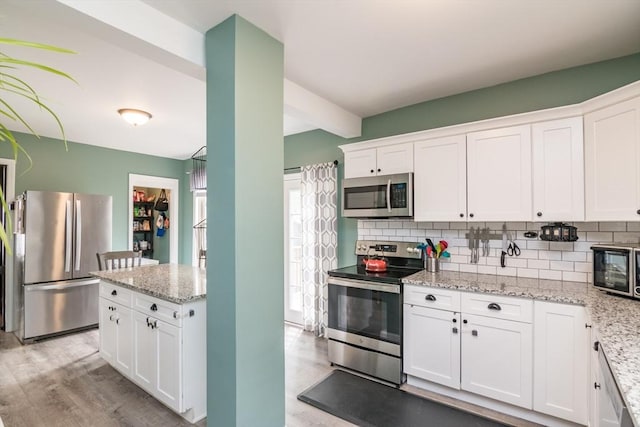 61 Fairfield Ave, Holyoke, MA 01040 - kitchen featuring stainless steel appliances, light wood-style flooring, white cabinetry, and tasteful backsplash