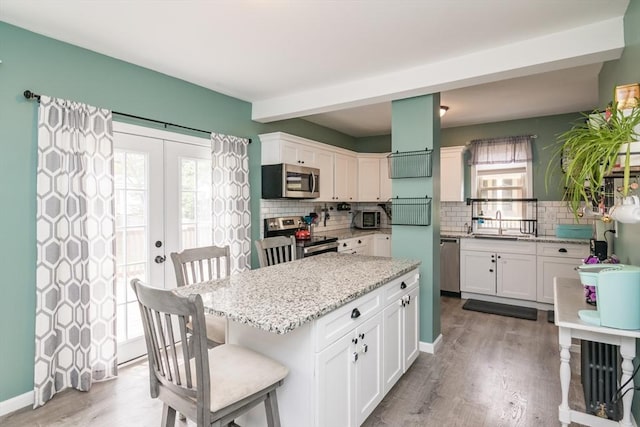 61 Fairfield Ave, Holyoke, MA 01040 - kitchen featuring stainless steel appliances, white cabinetry, tasteful backsplash, and wood finished floors
