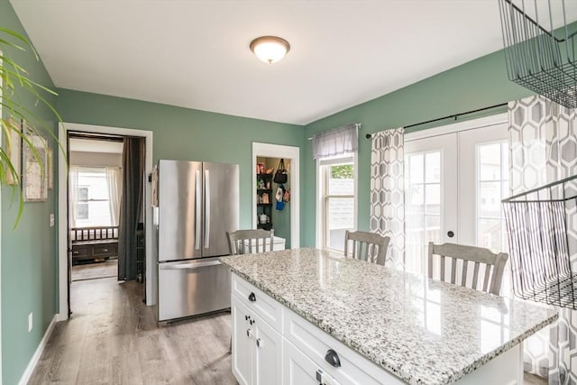 61 Fairfield Ave, Holyoke, MA 01040 - kitchen with freestanding refrigerator, light wood-style floors, white cabinets, and light stone counters