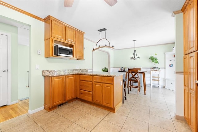 4 Charles River Rd, Medway, MA 02053 - kitchen featuring stainless steel microwave, a peninsula, crown molding, light stone counters, and light tile patterned floors