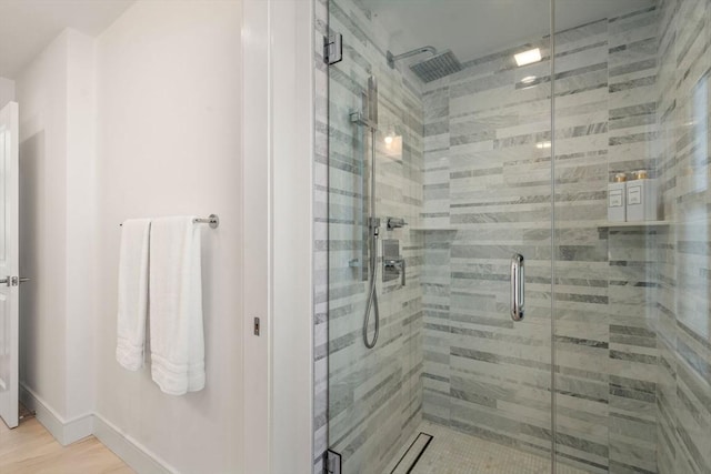 bathroom with wood finished floors, baseboards, and a stall shower