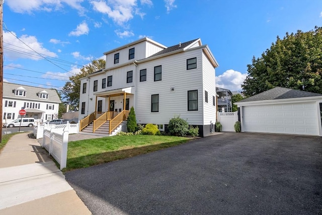 american foursquare style home featuring a detached garage, an outdoor structure, a front yard, and fence