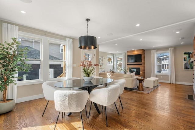 dining space with recessed lighting, wood finished floors, baseboards, and a large fireplace