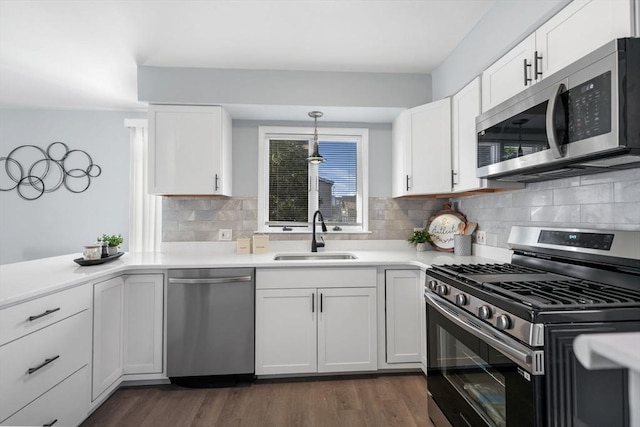 kitchen featuring stainless steel appliances, decorative light fixtures, white cabinetry, and sink