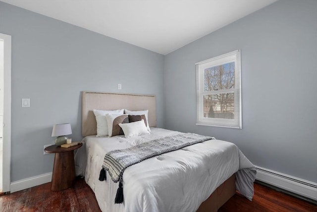 bedroom with dark hardwood / wood-style floors and a baseboard heating unit