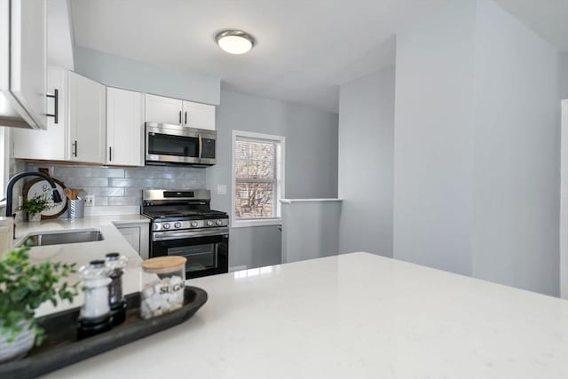 kitchen with white cabinets, appliances with stainless steel finishes, backsplash, and sink