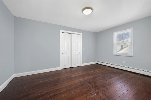 unfurnished bedroom with dark hardwood / wood-style flooring, a baseboard radiator, and a closet