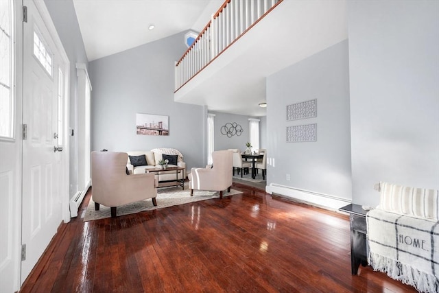 foyer entrance featuring baseboard heating, high vaulted ceiling, and wood-type flooring